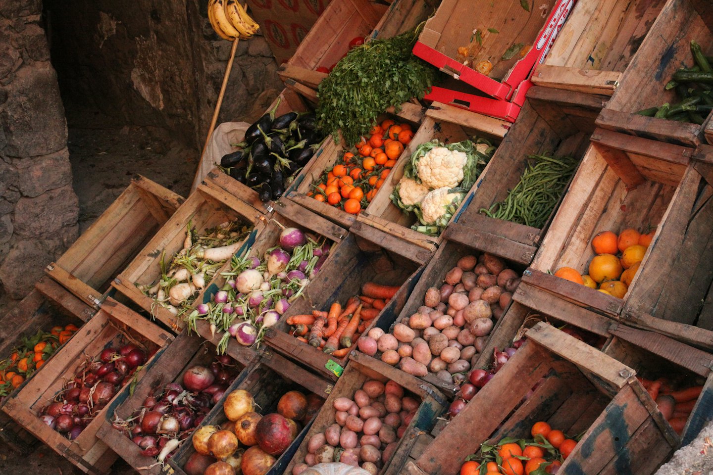Frutta e verdura fresca sono esposte in cassette di legno da mercato.