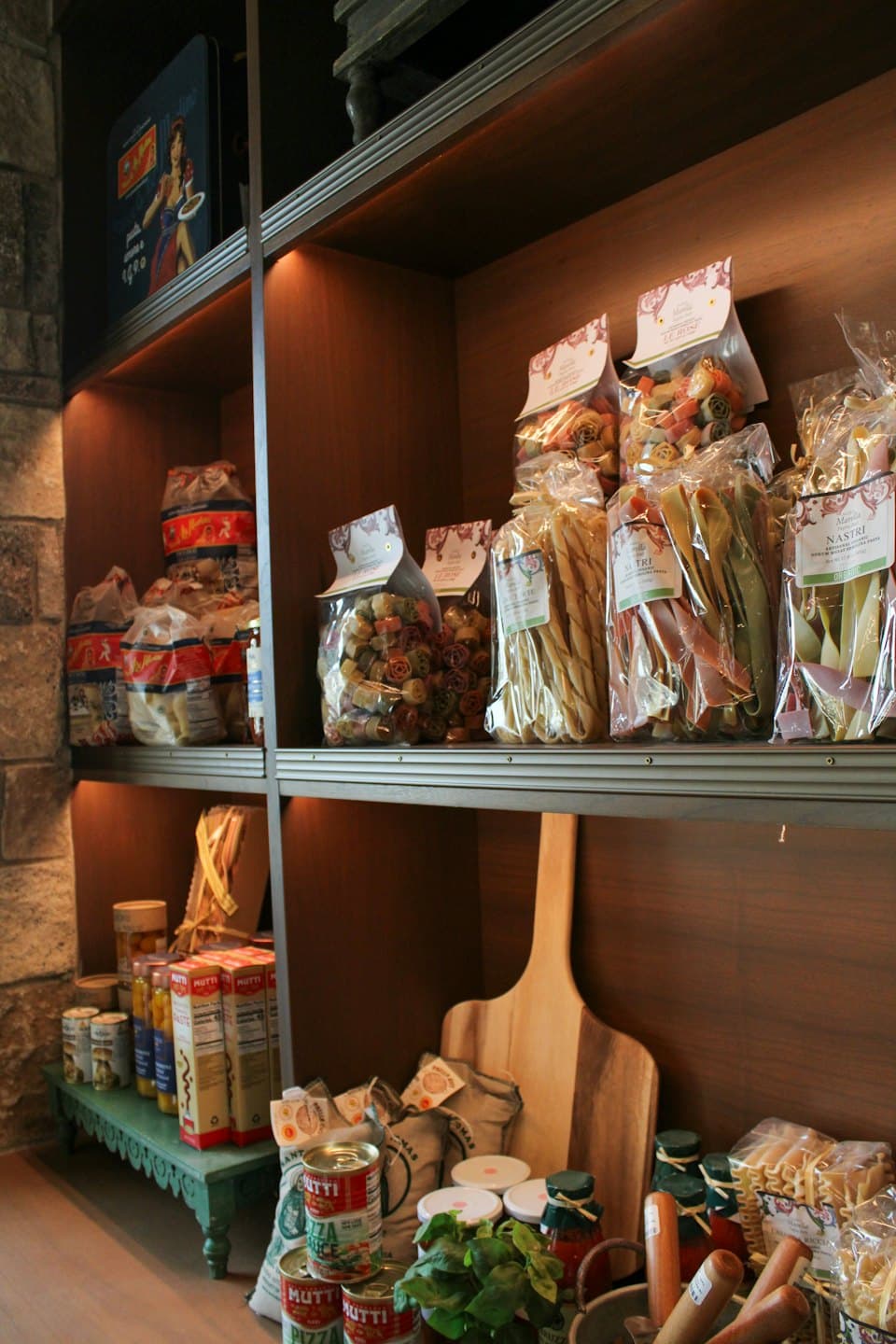 Prodotti alimentari italiani esposti su scaffali di legno in un negozio.